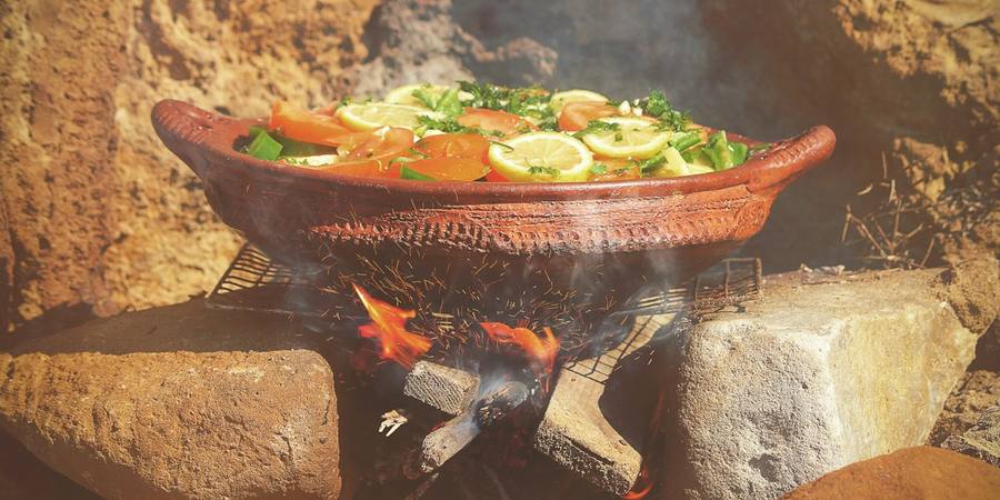 A tagine of vegetables cooking over an open fire