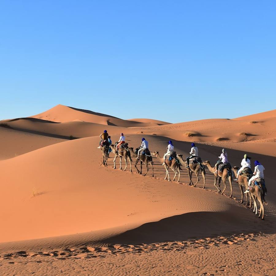 A line of camels and riders crossing the Erg Chebbi dunes