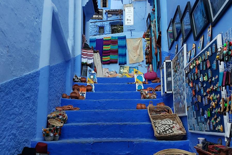 Blue stairs lined with baskets and textiles in Chefchaouen